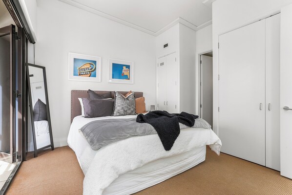 A hotel room with a bed, a wardrobe, a mirror, and two framed pictures on the wall.
