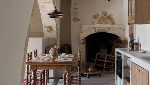 Une cuisine rustique avec une cheminée en pierre, une table à manger en bois et un four moderne.