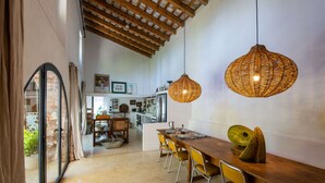 A dining area with a wooden table, yellow chairs, and a woven pendant light. - Historic Catalan country house located in a natural park and 40' from Barcelona! (Sant Llorenç Savall)