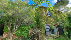 A rustic building partially covered with green vines, featuring a satellite dish and a window with shutters. - Historic Catalan country house located in a natural park and 40' from Barcelona! (Sant Llorenç Savall)