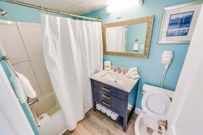 Ein Badezimmer mit Dusche, Waschbecken mit Spiegel und Toilette.