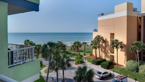 Un hotel con vista a la playa, palmeras y un estacionamiento.
