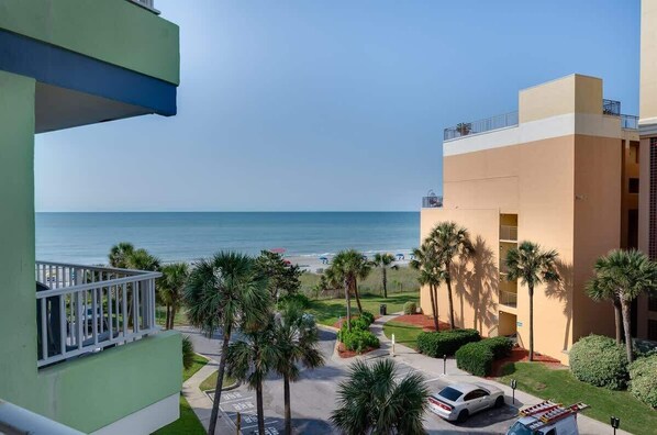 A hotel with a view of the beach, palm trees, and a parking area. - Newly Remodeled, Caravelle Resort, Amazing Pools! (Myrtle Beach)