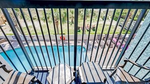 A balcony with a view of a pool and the ocean.