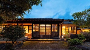 Una casa tradicional japonesa con fachada de madera, techo de tejas y un sendero de piedra que conduce a la entrada.