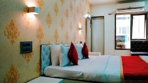 A hotel room with a bed, a wall socket, a mirror, and a window. - Hsquare Service Apartment Malad (Mumbai)