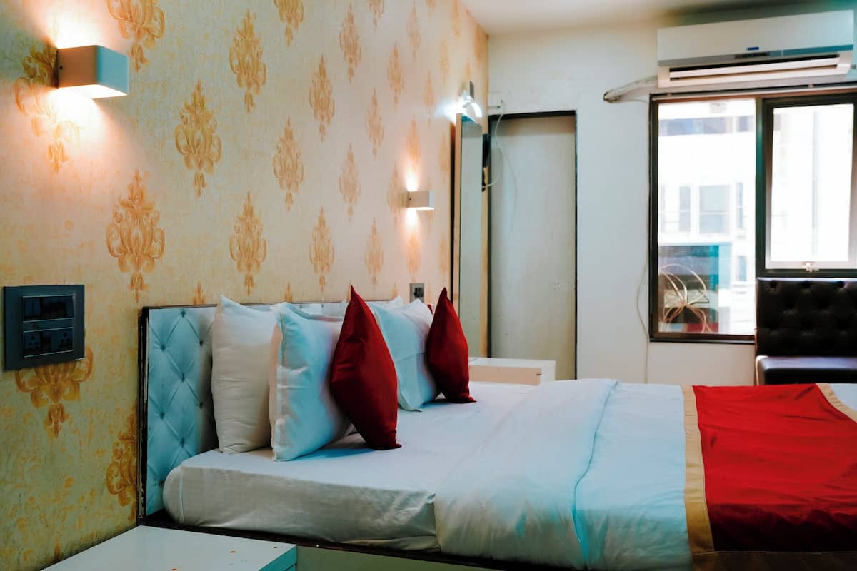 Quarto de hotel com uma cama, tomada, espelho e janela.