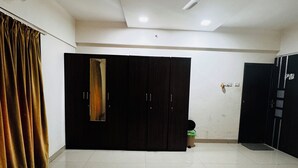 A hotel room with two beds, a ceiling fan, and a wardrobe. - Hsquare Service Apartment Malad (Mumbai)