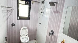 A small, compact bathroom with a toilet, a sink, and a shower. - Hsquare Service Apartment Malad (Mumbai)