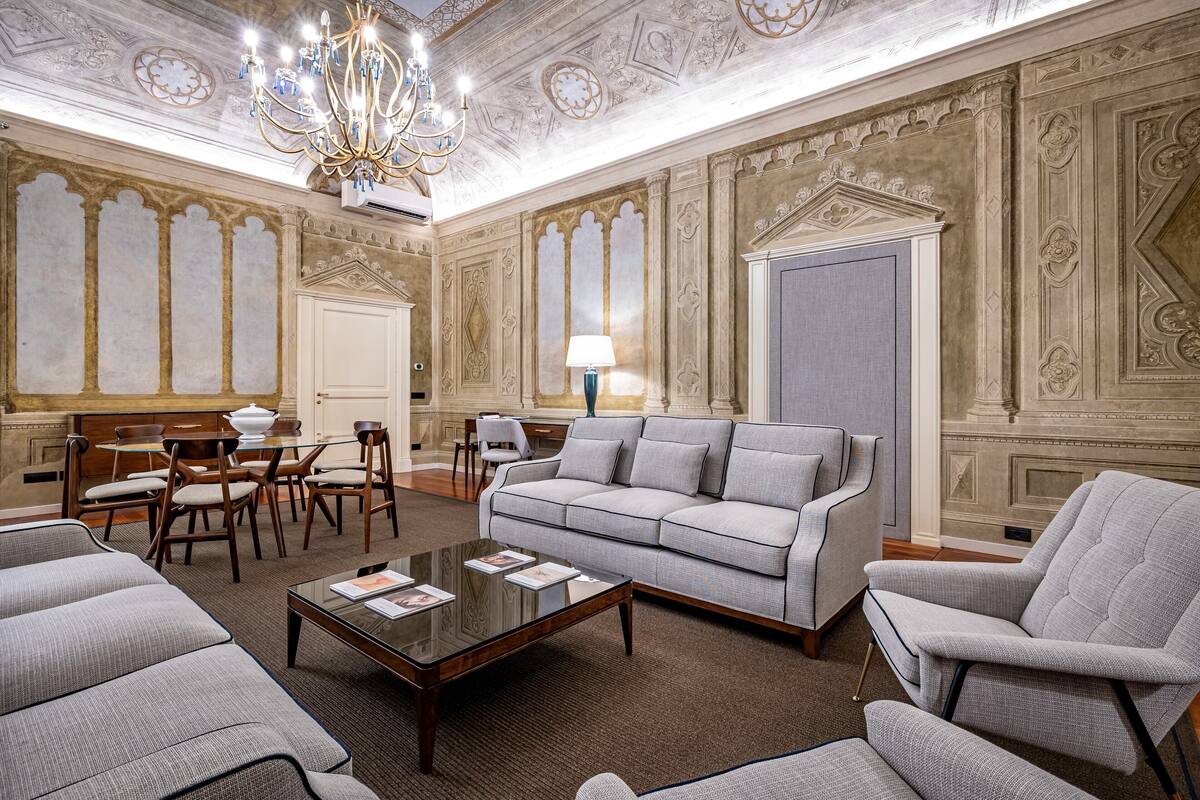 A spacious living room with a large sofa, armchairs, a coffee table, and a chandelier.