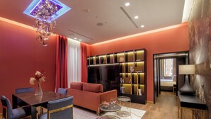 Un salon moderne avec un canapé rouge, une table à manger avec des chaises, un lustre et une bibliothèque.