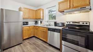 A modern kitchen with stainless steel appliances, wooden cabinets, and a window providing natural light.
