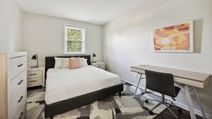A bedroom with a bed, bedside tables, a desk, and a chair. - Pine Brook 502 I Pool Gym I Free Parking ! (Newark)