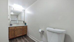 A bathroom with a wooden vanity, a toilet, and a mirror. - Pine Brook 502 I Pool Gym I Free Parking ! (Newark)