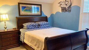 A bedroom with a bed, nightstand, lamp, and a wall-mounted artwork. - Beach front vacation house (Myrtle Beach)