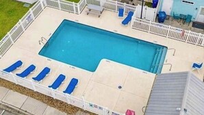 A rectangular swimming pool with a white deck and blue lounge chairs. - Beach front vacation house (Myrtle Beach)