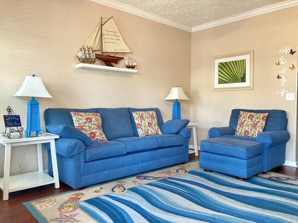 Un salón con un sofá azul, un tapete estampado y cojines decorativos.