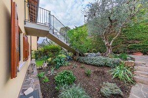 A garden with a stone pathway, a wooden staircase, and a variety of plants.