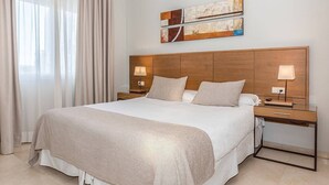 A hotel room with a large bed, two bedside tables with lamps, a wooden headboard, and a modern abstract painting above the bed. - Aparthotel Ona Alanda club, luxury.40 meters from the beach.spectacular views. (Marbella)