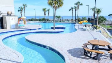 A swimming pool with a curved design, surrounded by palm trees and a view of the ocean.