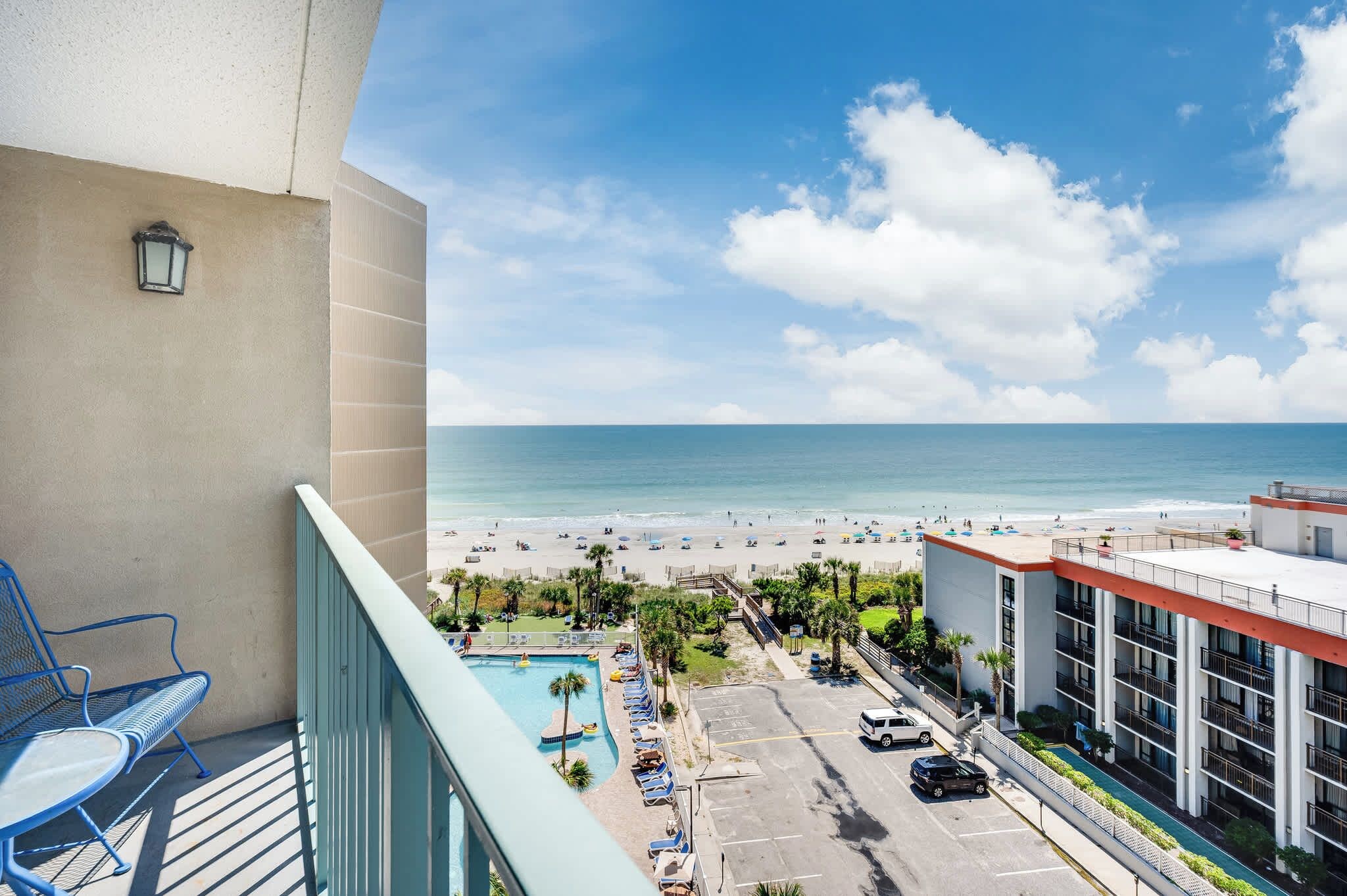 A balcony with a view of a beach and a swimming pool.