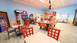 A gaming arcade with various machines, red chairs, and tables. - Oceanfront Studio - Indoor Pools, Hot Tubs, Nice! (Myrtle Beach)
