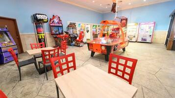 A gaming arcade with various machines, red chairs, and tables.