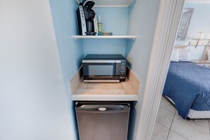 A compact kitchenette with a microwave, a coffee maker, and a small shelf with items. - Oceanfront Studio - Indoor Pools, Hot Tubs, Nice! (Myrtle Beach)