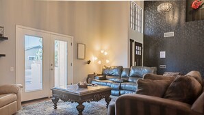 Een woonkamer met een leren bank, een bijzettafeltje en een kroonluchter.