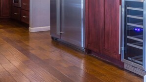 Een moderne keuken met houten kastjes, roestvrijstalen apparatuur en een geïntegreerde wijnkoeler.