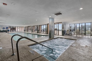 An indoor swimming pool with a hot tub, surrounded by glass walls and a view of the outdoors. - New 1BR Direct Oceanfront, Sandcastle South, Pools (Myrtle Beach)
