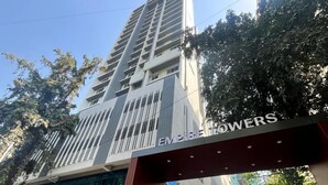 En modern höghusbyggnad med en framträdande entré och en skylt med texten ”EMPIRE FLOWERS”.