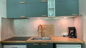 Et kompakt køkken med turkise skabe, en træbordplade, en Bosch opvaskemaskine og et Frigidaire køleskab.