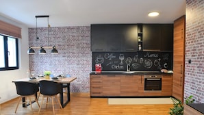A modern kitchen with a brick wall, wooden cabinets, and a chalkboard menu.