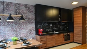 A modern kitchen with a brick wall, wooden cabinets, and a chalkboard menu.