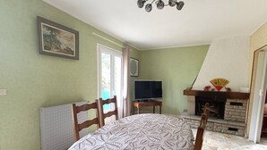 A room with a bed, a television, a fireplace, and a door leading outside. - Charming House near Beach with WIFI, Garden & Terrace - Pleumeur-Bodou (Pleumeur-Bodou)