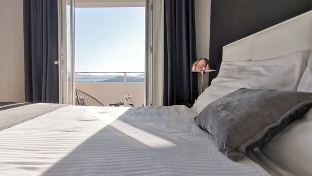 Une chambre d’hôtel avec un lit, une table de chevet et une vue sur les montagnes par la fenêtre.