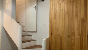 A staircase with white walls and wooden steps leading to a door with a brass handle. - 3-room Duplex for 6 at slopes, south terrace (Pra-Loup)