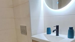 Une salle de bain moderne avec des toilettes, un lavabo et un miroir.