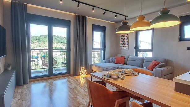 Un salon moderne avec un coin repas, de grandes fenêtres et un balcon.