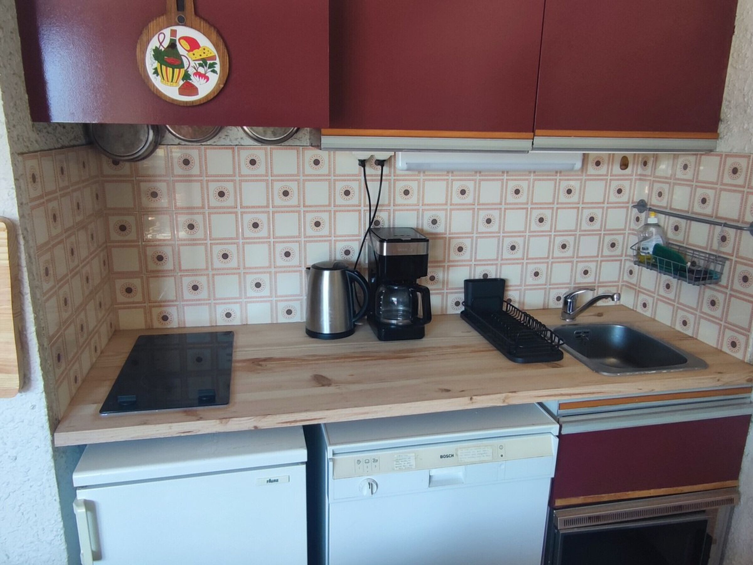 Una cuina compacta amb un rentaplats Bosch, una cafetera i un rentamans.