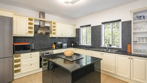 A modern kitchen with white cabinets, a central island, and a black countertop. - Casa Cegonha - spacious villa with heated pool (Carvoeiro)