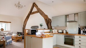 A modern kitchen with a central island, white cabinetry, and a rustic wooden beam arching above.