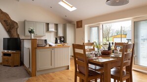 A modern kitchen with white cabinets, a wooden dining table, and a large window.