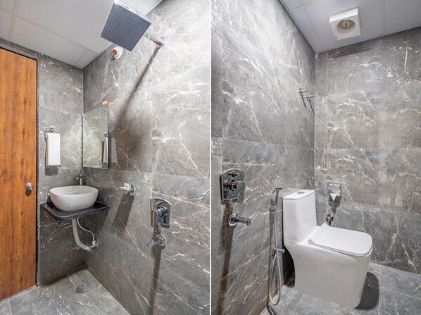 A modern bathroom with a marble wall, a wooden door, a sink, a toilet, and a shower.
