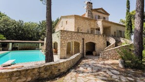 Une villa en pierre dotée d’une piscine, d’un escalier en pierre et offrant une vue sur les arbres environnants.
