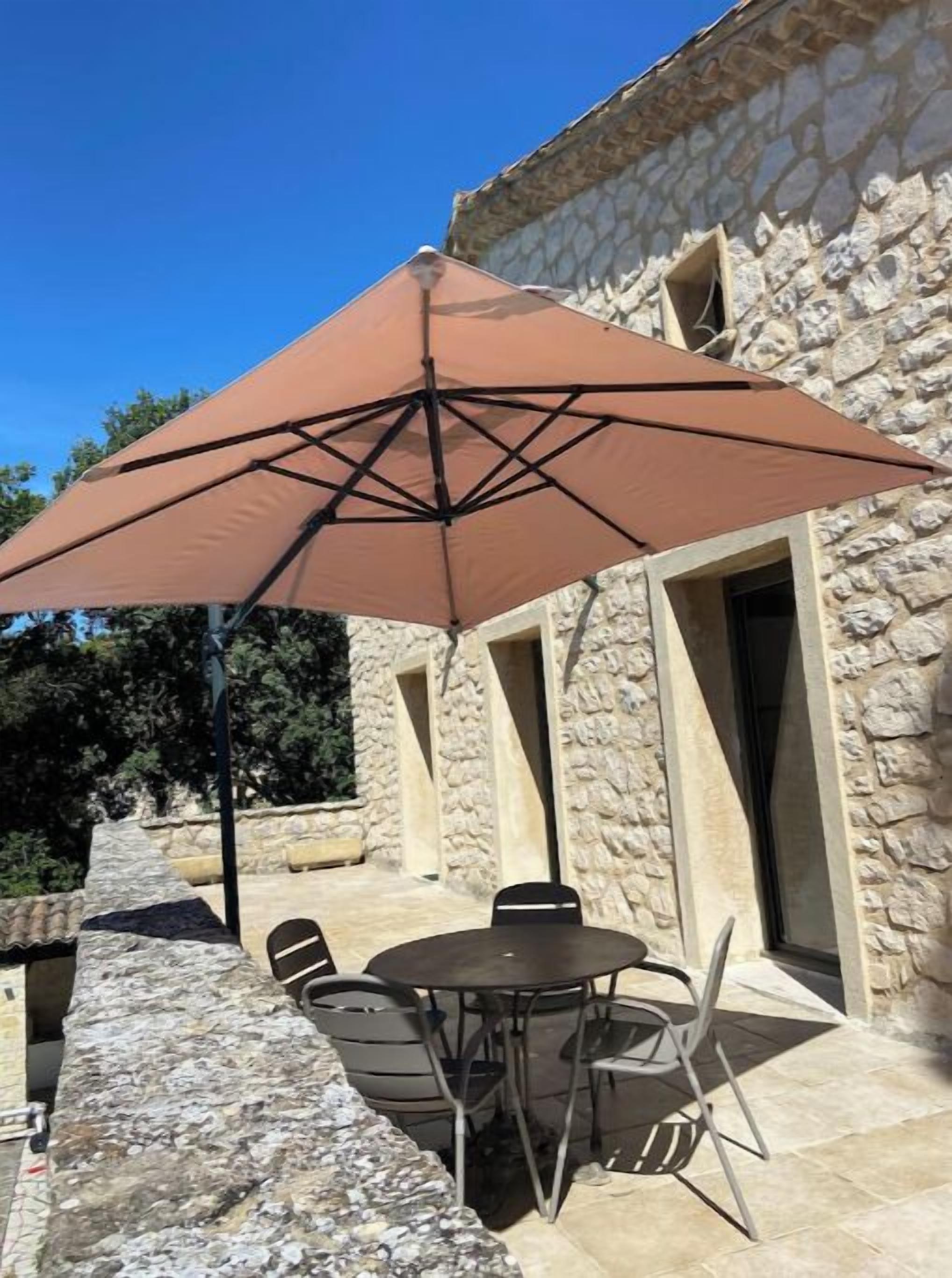 An outdoor patio with a stone building, a round table, and four chairs.