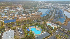 Vista aérea de una zona residencial con una gran piscina rodeada por un estacionamiento y algunos edificios.