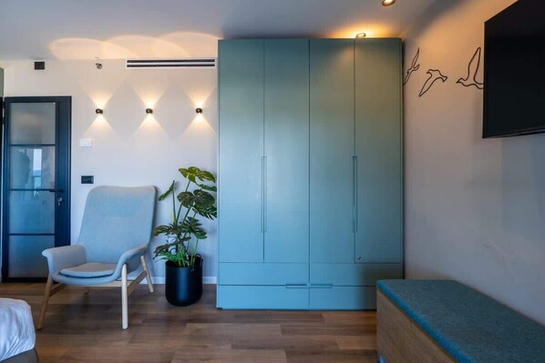 A modern room with a light blue wardrobe, a grey armchair, a potted plant, and a bench.