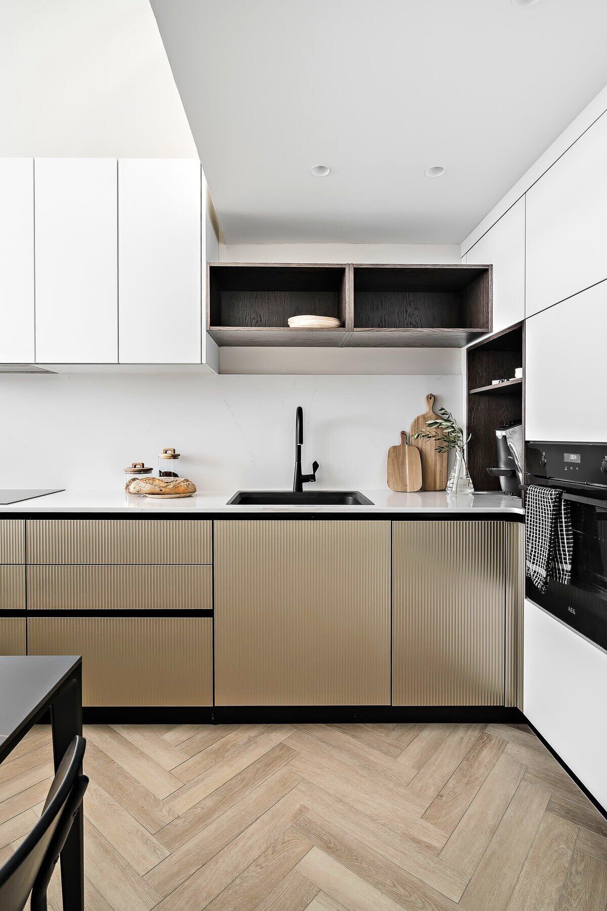 A modern kitchen with a herringbone wood floor, a black faucet, and a built-in oven.